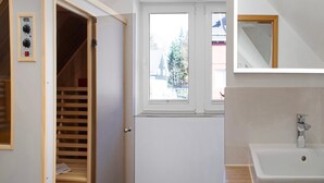 A bathroom with a bathtub, a window, and a wooden closet with a control panel.
