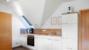 A modern kitchen with white cabinets, a built-in oven, a coffee maker, and a wooden countertop.