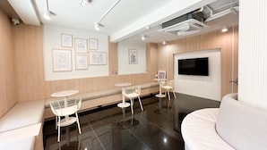 A modern interior with a seating area, a flat-screen TV, and artwork on the walls. - Ascella Pratunam Hotel (Bangkok)