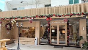 A hotel entrance with a modern facade, large windows, and festive Christmas decorations. - Ascella Pratunam Hotel (Bangkok)