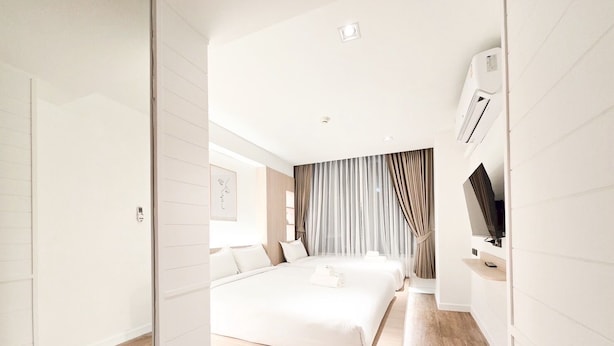 A modern hotel room with a large bed, a TV, and a sliding door leading to a balcony. - Ascella Pratunam Hotel (Bangkok)
