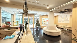 A modern lobby with a marble reception desk, a round seating area, and a Christmas tree. - Ascella Pratunam Hotel (Bangkok)
