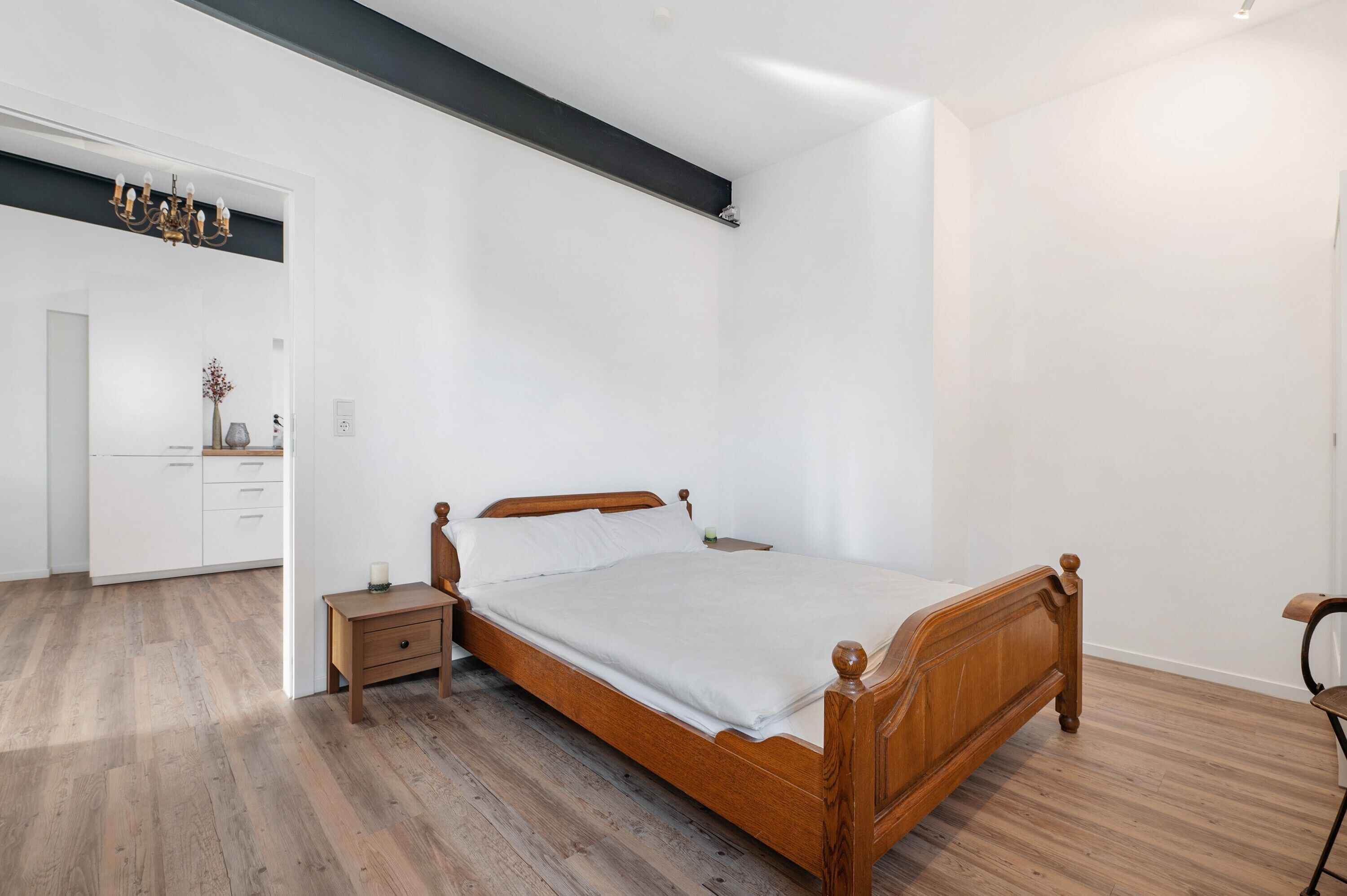 Une chambre à coucher avec un lit en bois, une table de chevet, une commode et un miroir.