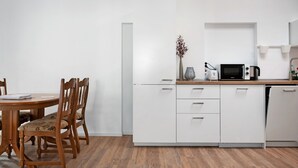 A modern kitchen with white cabinets, a wooden dining table, and chairs. - Apartment 'Die Alter Schwede 2' with Shared Terrace and Wi-Fi (Vechta)