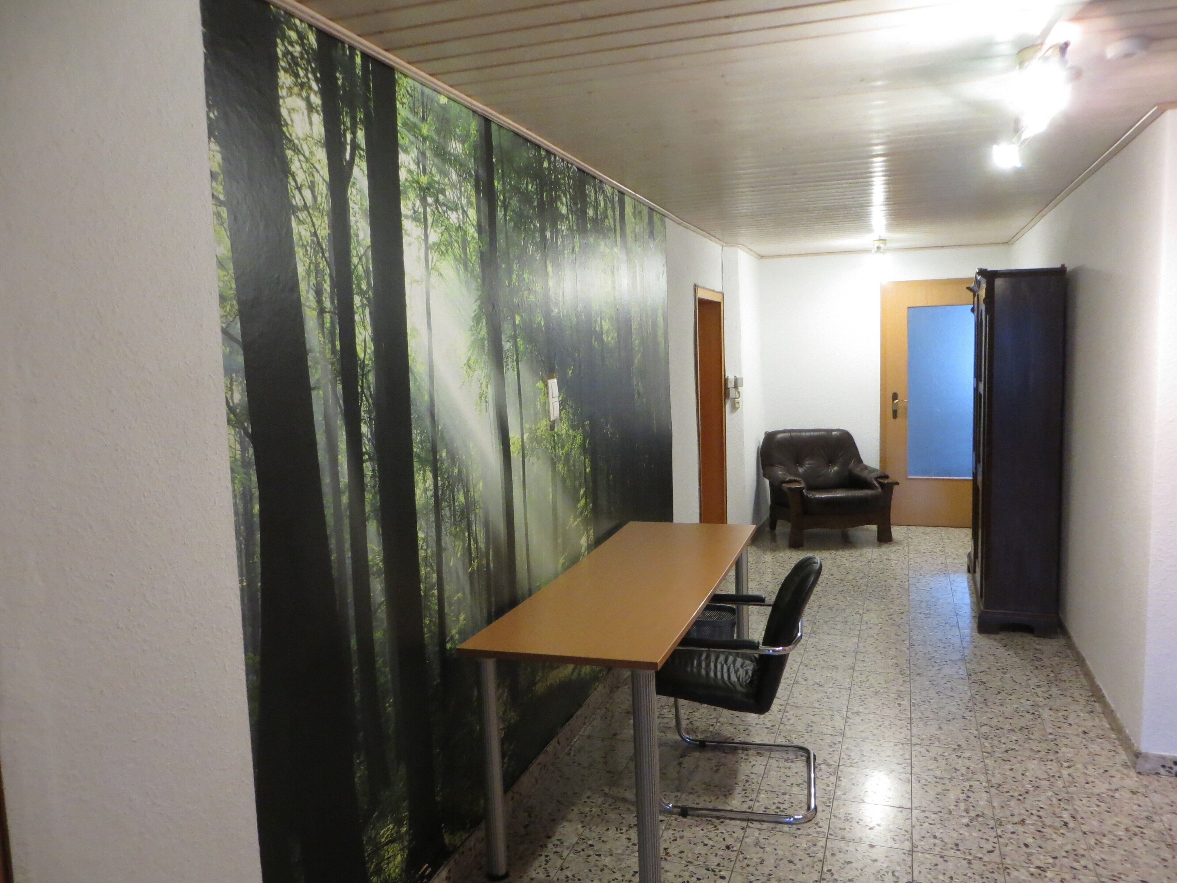 Una sala de conferencias con una mesa larga, dos sillas, un sillón de cuero negro, una pizarra y una puerta.
