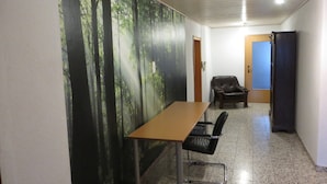 A conference room with a long table, two chairs, a black leather chair, a whiteboard, and a door.