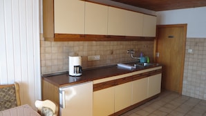 A compact kitchen with a built-in coffee maker, a sink, and wooden cabinets.