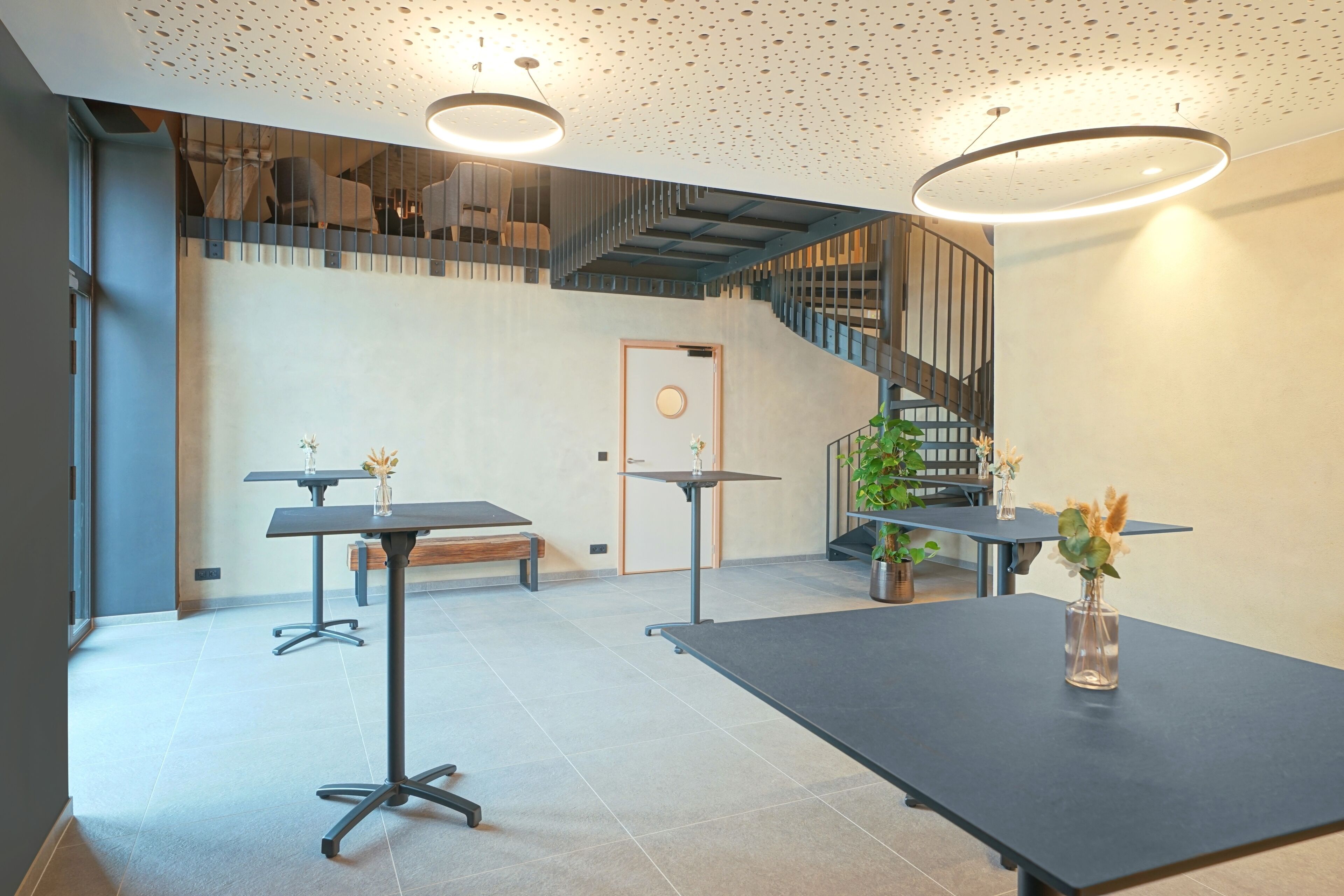 Ein modernes Interieur mit Treppe, Tischen und einer Bank.