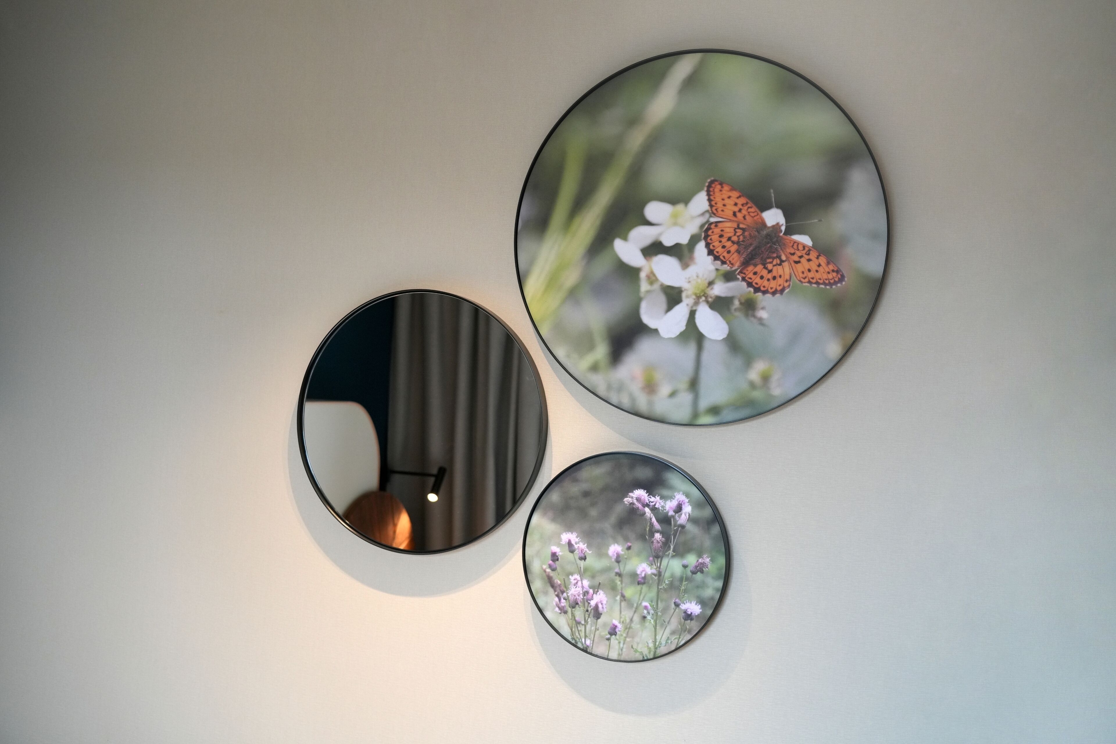 Drei runde Wandspiegel mit verschiedenen floralen Fotografien.