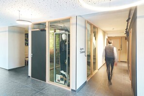 Contemporary corridor with a glass partition and a sign indicating the location of the restroom.