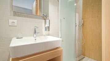 A bathroom with a white sink, a mirror, and a glass shower enclosure.