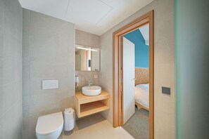 Een moderne badkamer met toilet, wastafel en spiegel.