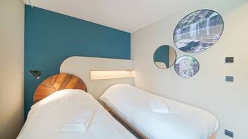 A hotel room with two beds, a wooden headboard, a teal accent wall, and circular wall art depicting nature scenes.