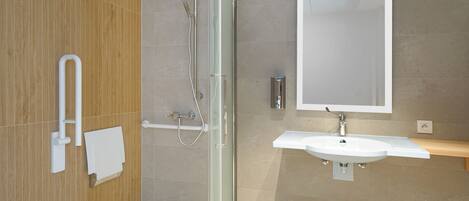 A modern bathroom with a glass shower enclosure, a white sink, and a large mirror.