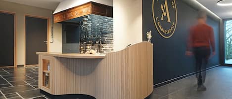 Un área de recepción moderna con una recepción de madera curva, una pared de piedra y un logotipo en la pared.