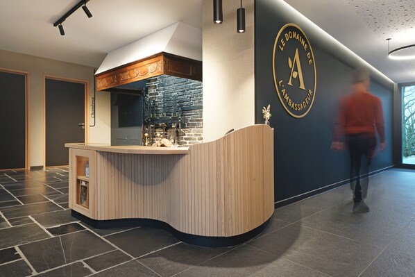 Een moderne receptiebalie met een gebogen houten toonbank, een stenen muur en een logo op de muur.