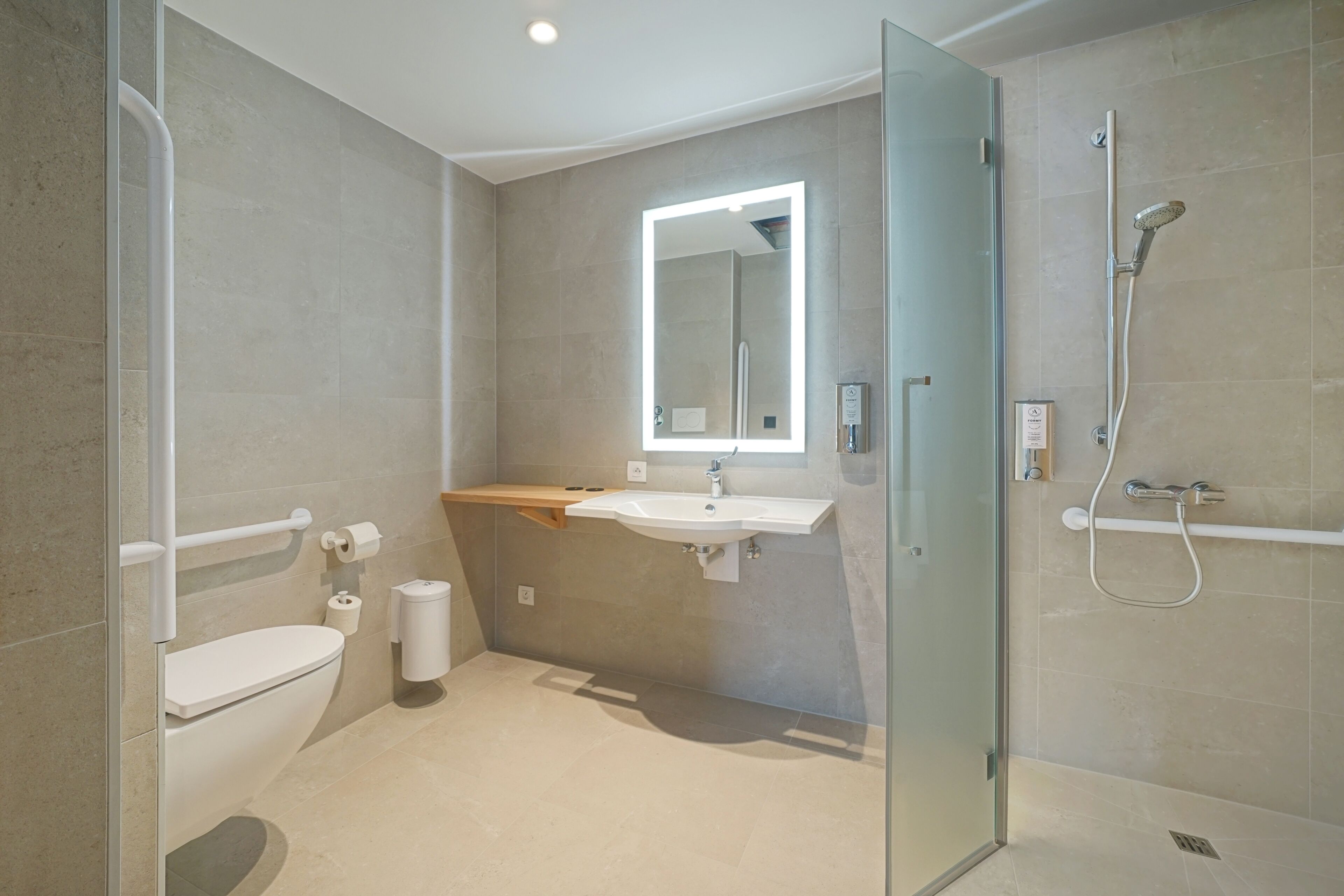 Un baño moderno con cabina de ducha de vidrio, un lavabo blanco y un espejo sobre él.