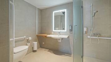 Un baño moderno con cabina de ducha de vidrio, un lavabo blanco y un espejo sobre él.