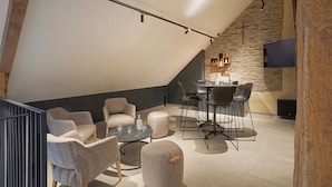 Un espace moderne de style loft comprenant un coin repas, un espace détente et un mur d’accent en pierre.