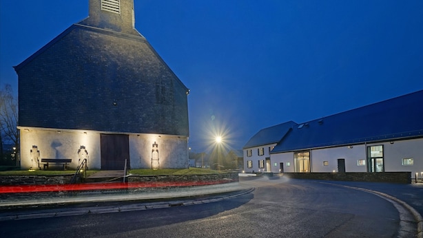 Un grand bâtiment en briques, doté d’un toit en forme de pignon et d’une petite structure adjacente.