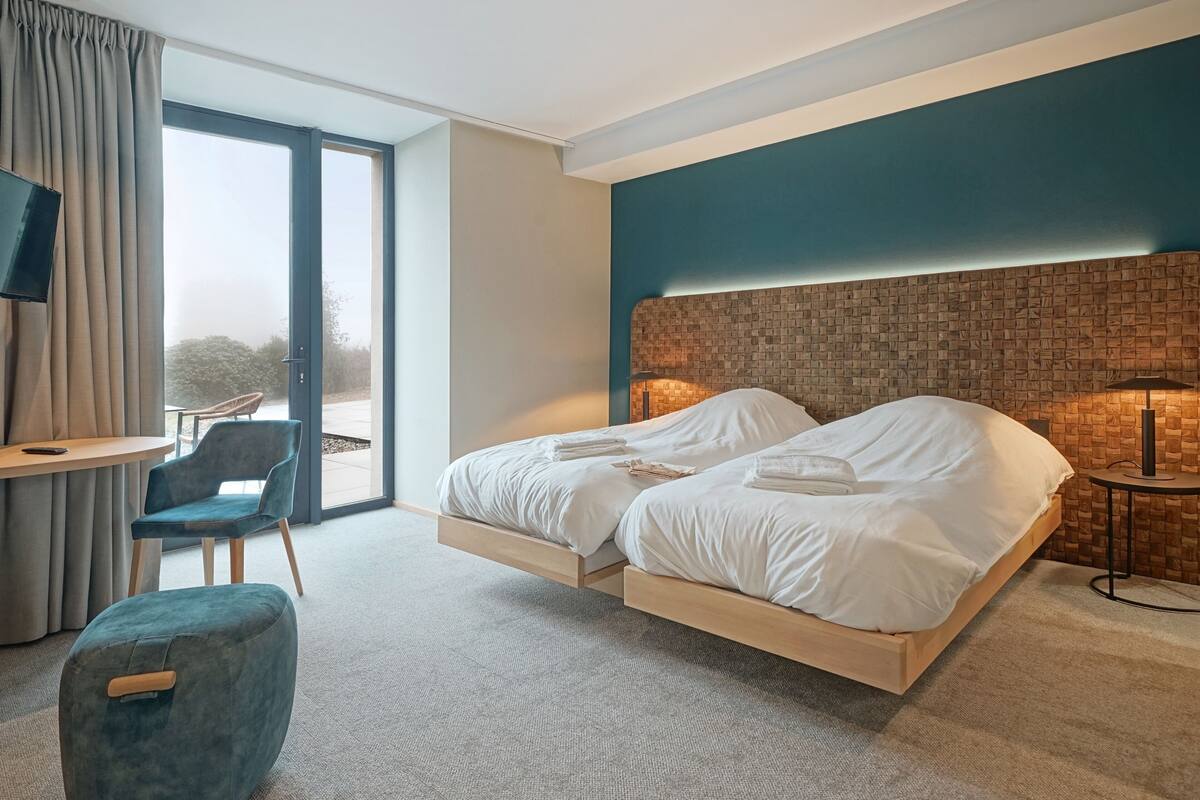 A modern hotel room with a large bed, a desk, and a chair.