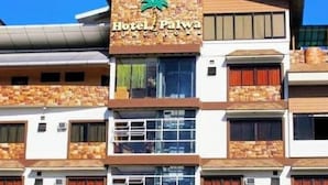A multi-story hotel with a stone facade, balconies, and a palm tree logo. - Hotel Palwa (Dumaguete)