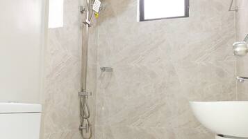A modern bathroom with a toilet, a shower, and a sink.