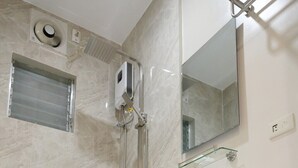 A modern bathroom with a white toilet, a glass shower enclosure, and a marble-tiled wall. - Hotel Palwa (Dumaguete)