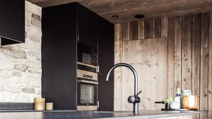 A modern kitchen with a stone wall, wooden ceiling, and a bar area with stools. - Modern Maison Near Somme-leuze (Somme-Leuze)