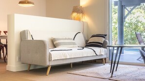 Un salon moderne avec un canapé, une lampe et une vue à travers une porte vitrée.