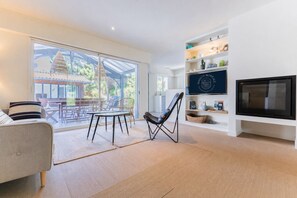 Een moderne woonkamer met een bank, een eettafel, een stoel, een televisie en een boekenkast.
