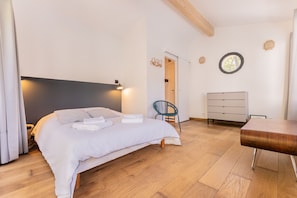 Ein Schlafzimmer mit Bett, Stuhl, Kommode und einem kleinen Tisch.