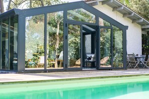 A glass-enclosed structure with a pool in the foreground. - Villa au Pyla avec Piscine, Plage & Dune à pied (Pyla-sur-Mer)