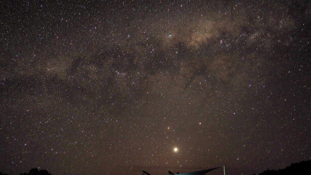 A small, illuminated structure under a starry night sky with a visible moon. - Poolside Ocean View Pod (Marion Bay)