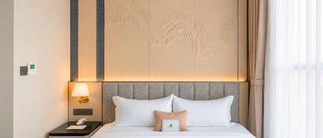 Una camera d'albergo con un letto, un comodino, una lampada e un pannello decorativo a parete.