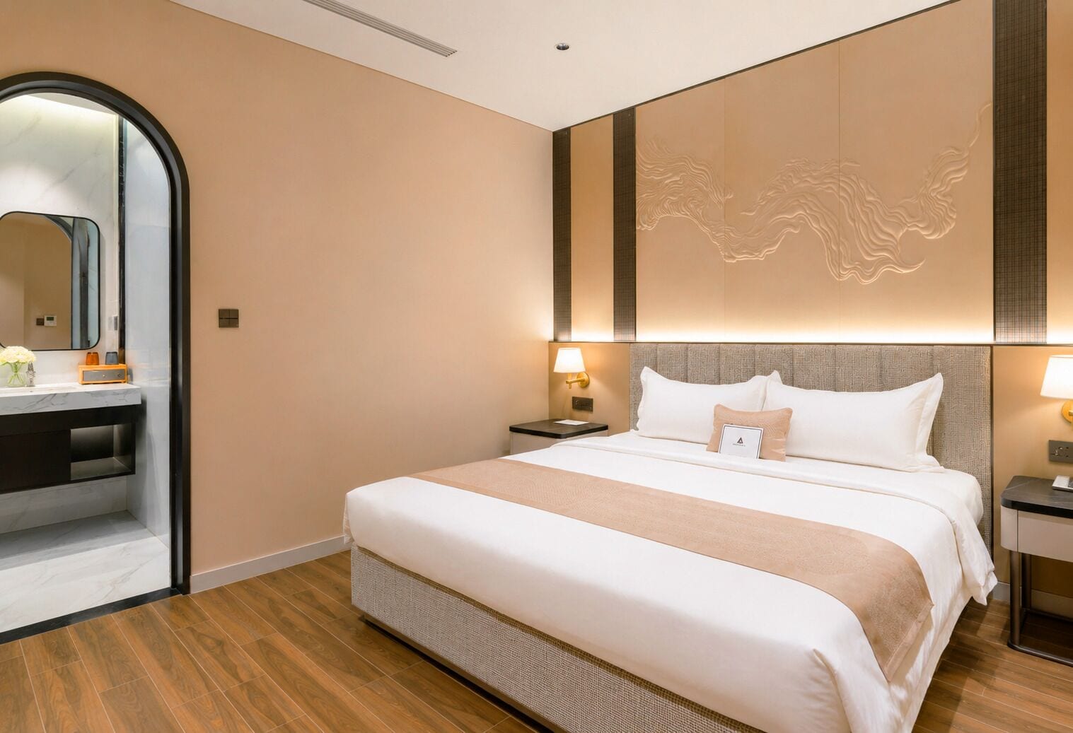A hotel room with a large bed, bedside lamps, a mirror, and a wooden floor.