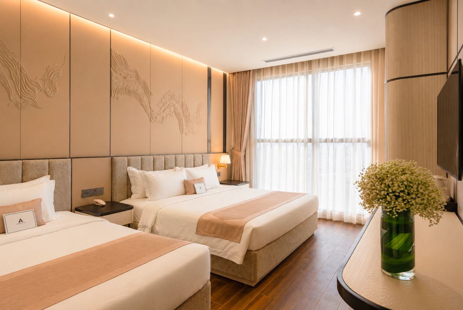 Une chambre d’hôtel avec deux lits, une grande fenêtre avec des rideaux légers, un téléviseur fixé au mur et un vase rempli de fleurs placé sur une table d’appoint.