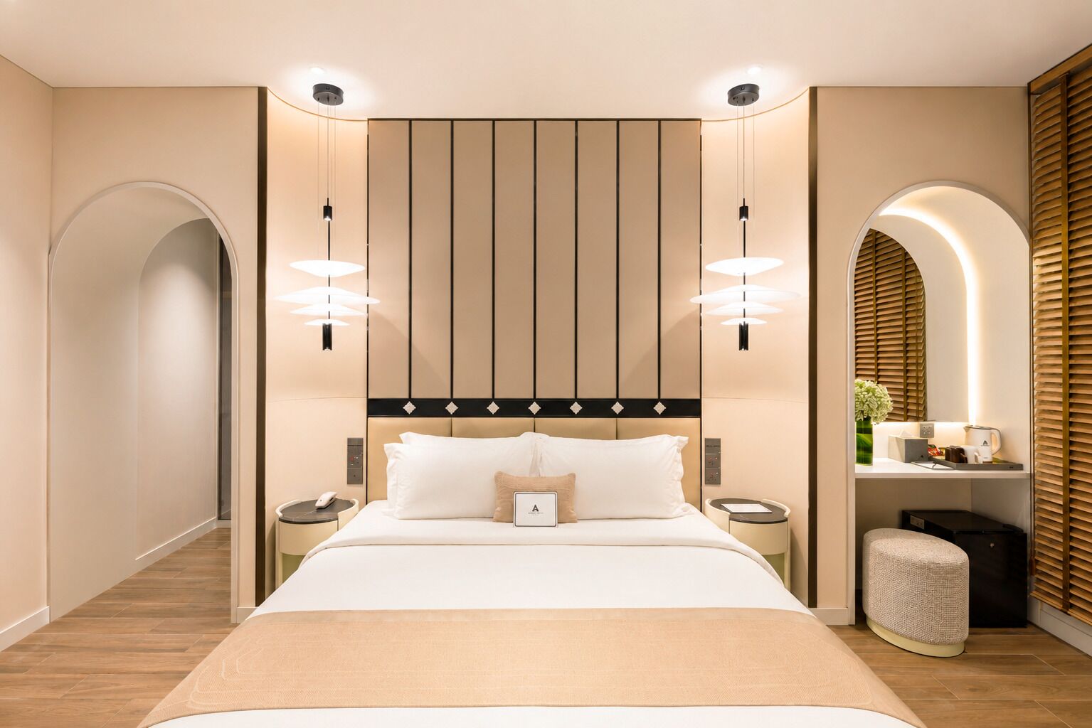Een moderne hotelkamer met een groot bed, nachtkastjes, een zithoekje en een wandlamp.