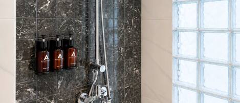 A modern bathroom with a shower, marble tiles, and a window with frosted glass.