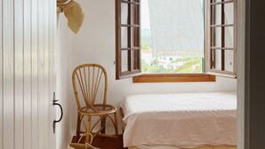 Un dormitorio con cama, una silla, un ventanal y vistas al exterior.