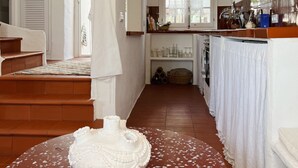 Una cocina amplia con una isla central, un comedor con mesa y sillas, y una escalera que sube a otro nivel.