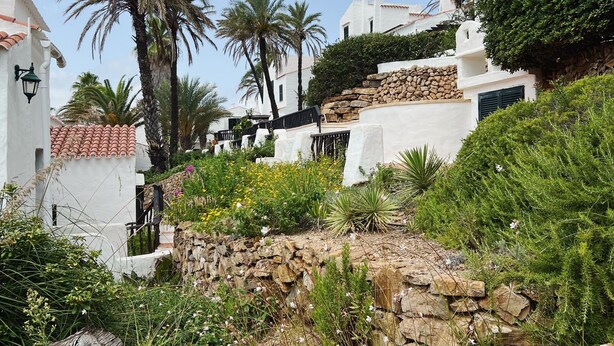 Un edificio blanco con pared de piedra y palmeras.