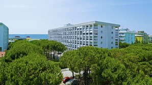 A modern hotel with a central courtyard, surrounded by lush greenery and a view of the sea. - Apartment with sea view terrace (Bibione)