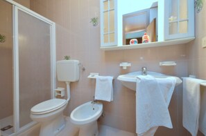 A bathroom with a toilet, bidet, and sink, all with white fixtures and towels. - Seafront studio in Bibione (Bibione)