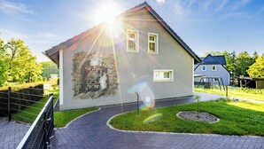 A house with a mural, a small garden, and a paved pathway. - Vacation home Bimmelbahn track 2 (Olbersdorf)