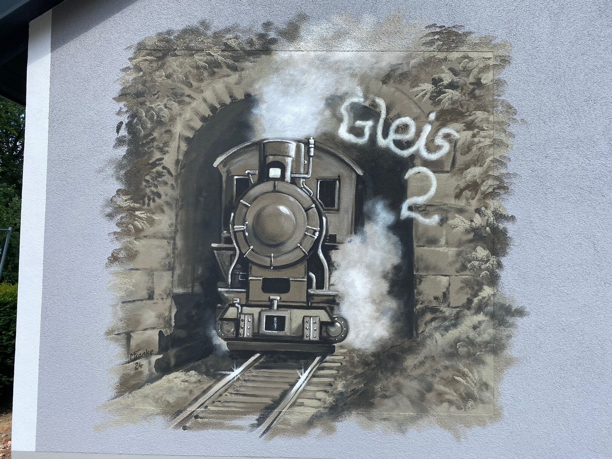 Une fresque représentant un train à vapeur entrant dans un tunnel, avec l’inscription « Gleis 2 » visible.