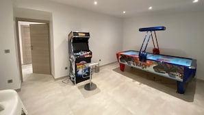 A room with a pool table, a gaming machine, and a door leading to another room. - ✨ Maison Calypso – Luxury Lakefront Villa with Hot Tub & Sauna (GERARDMER)
