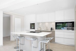 A modern kitchen with white cabinetry, a marble countertop, and stainless steel appliances.