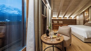 A cozy room with a bed, a small table with snacks, and a view of a snowy mountain. - Casa Guargne' (Cortina d'Ampezzo)