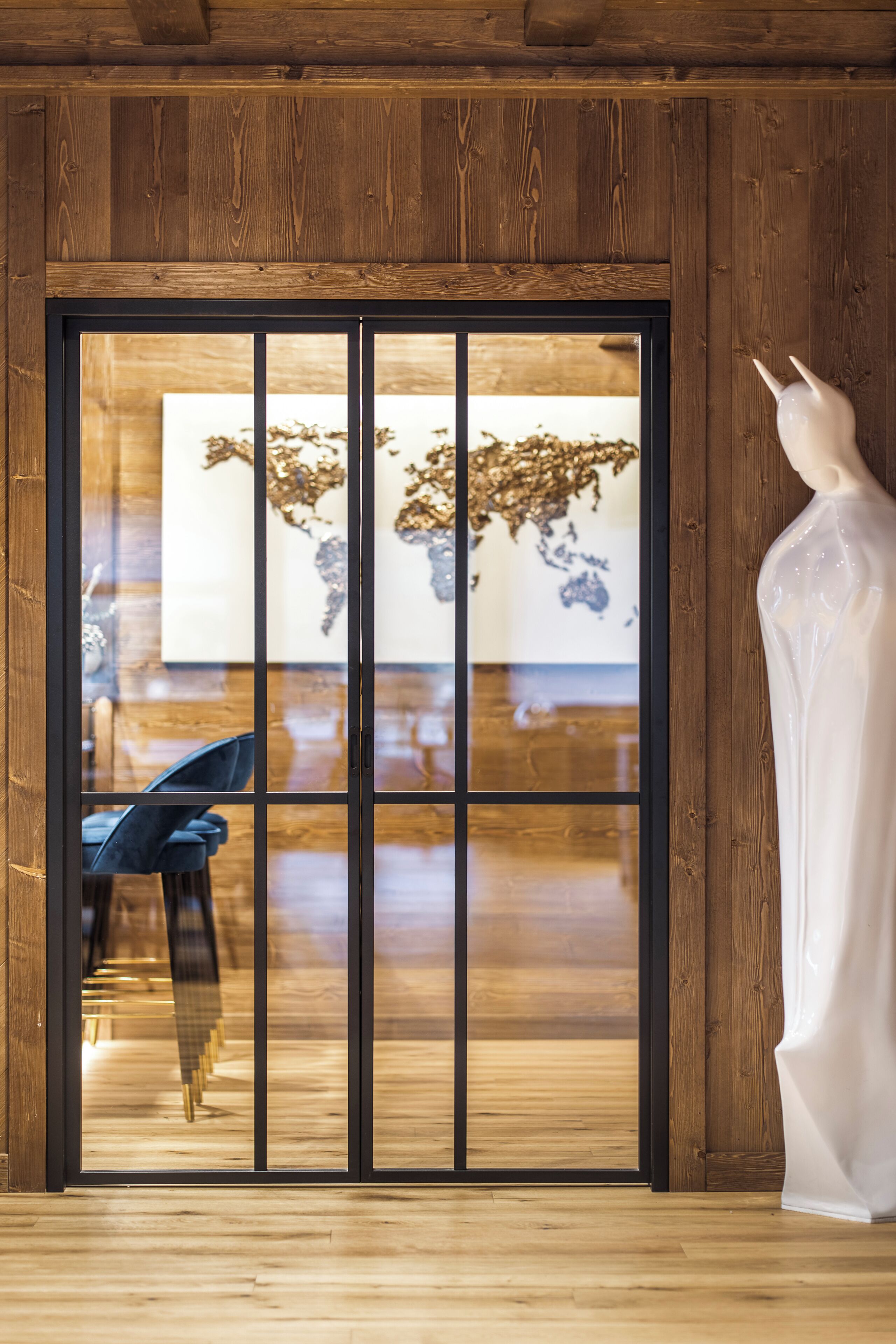 A wooden-framed sliding door with a glass panel, a mannequin, and a blue chair inside.